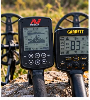Illustrative image of two metal detector control boxes with displays resting on a rock outdoors