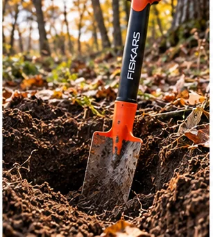 Illustrative image of a digging tool standing in a freshly dug hole in dark soil